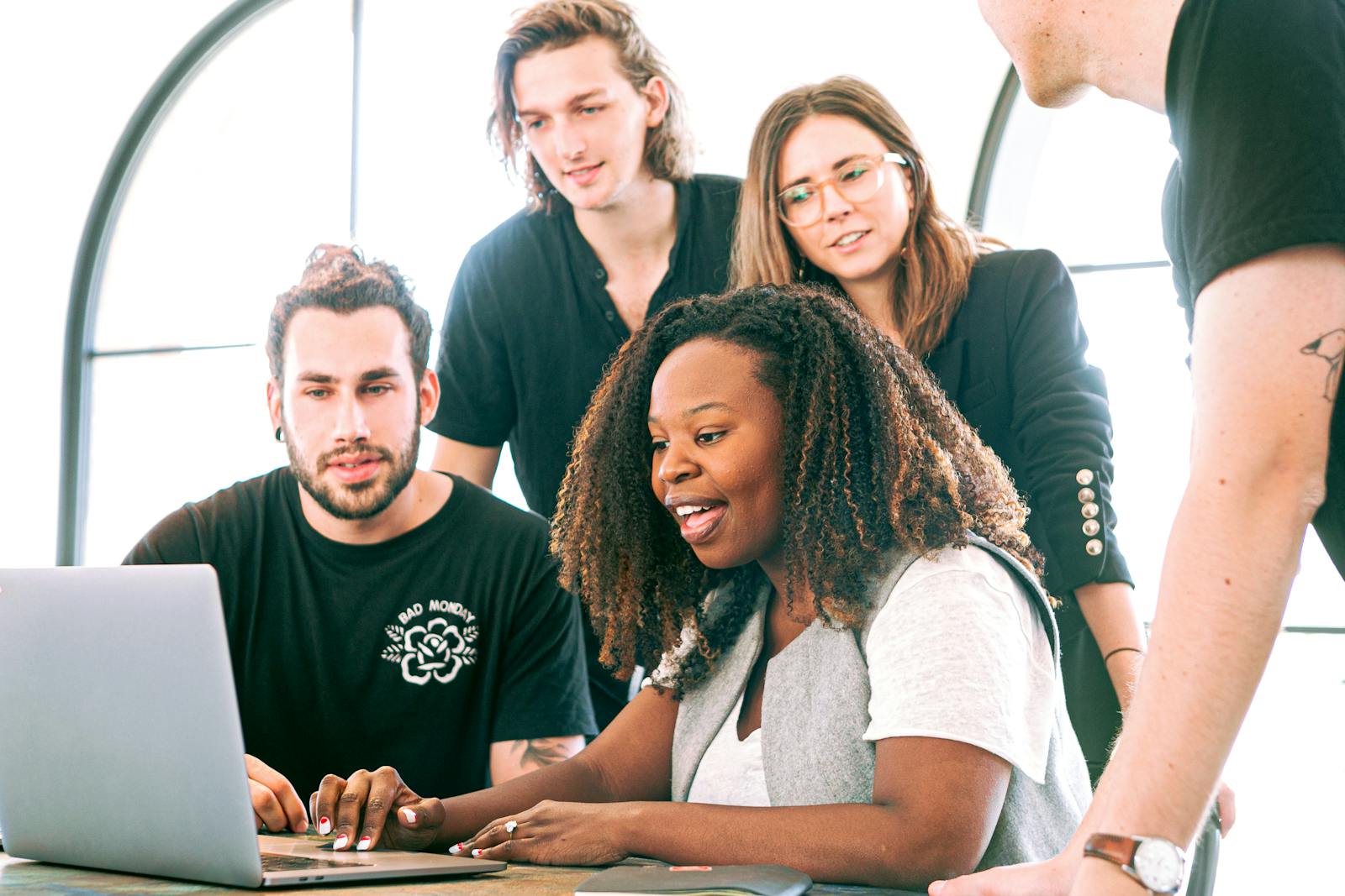 A diverse group of young professionals collaborating around a laptop in a modern office setting. Perfect for business or tech concepts. startup