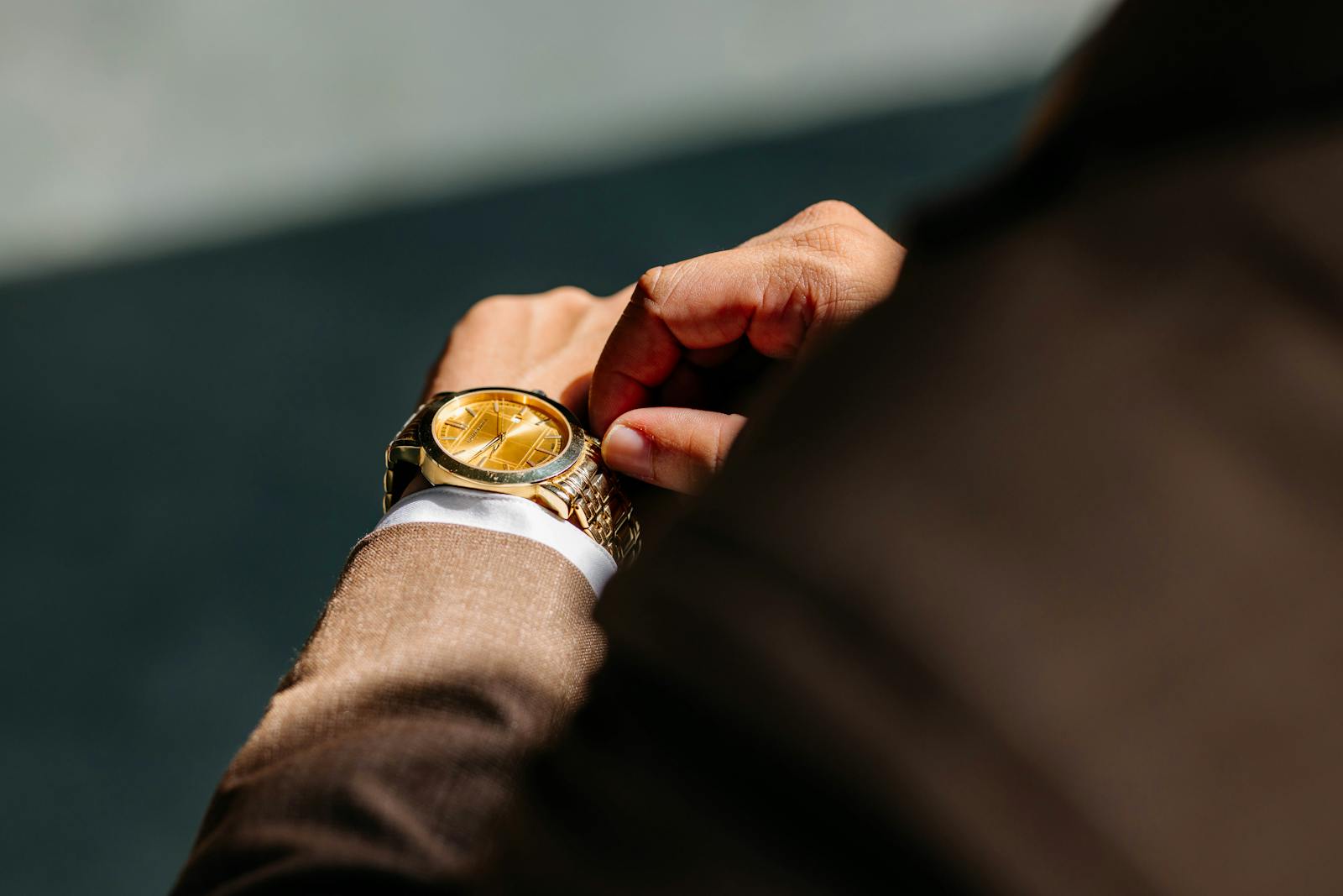 Close-up of a luxurious gold wristwatch being worn by a man in a suit, showcasing fashion and elegance.