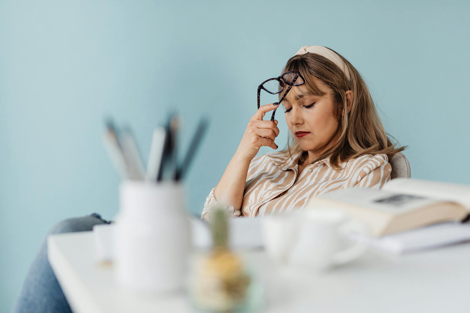 Woman looks exhausted while taking a break with eyes closed at her desk.